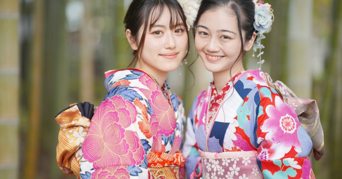 色鮮やかな着物姿の女性二人が寄り添って笑顔を見せる様子