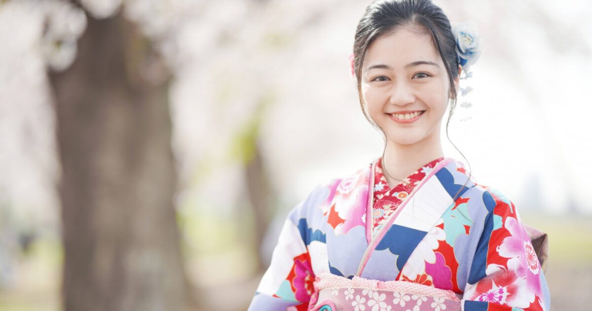 桜の木の前で微笑む着物姿の女性のポートレート