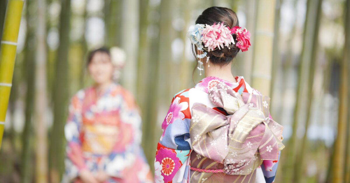竹林の中で着物姿の女性が友人に向き合う後ろ姿