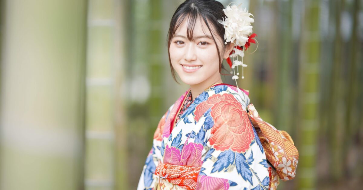 色鮮やかな着物を着た女性が竹林で微笑む様子