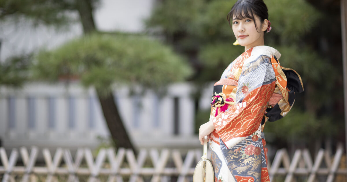 伝統的な着物を着た女性が庭園でたたずむ様子