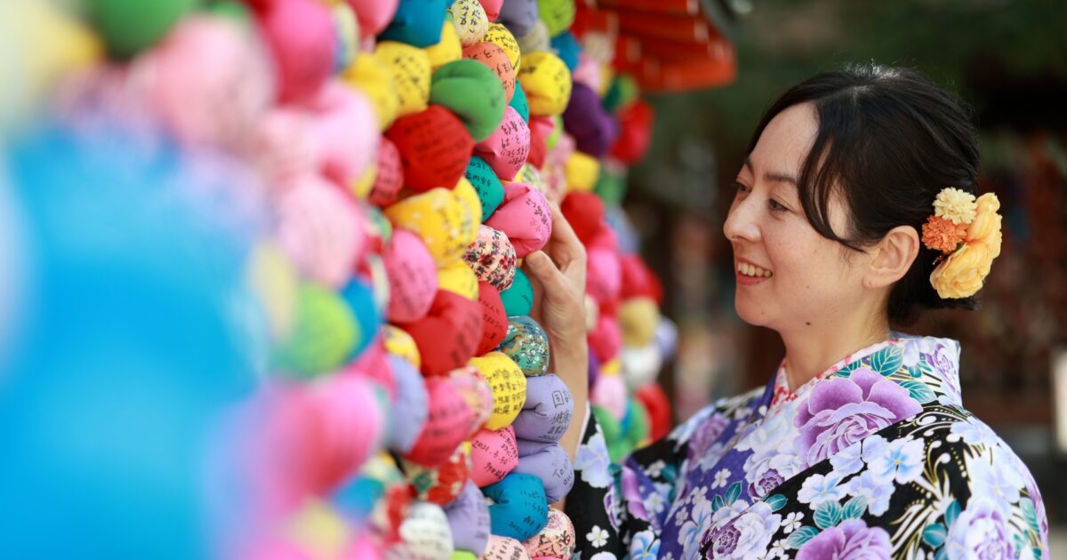 色とりどりのくくり猿を触る着物姿の女性