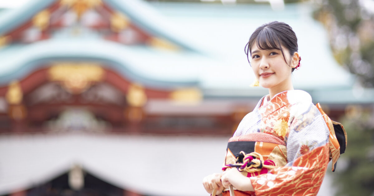 神社の前で微笑む振袖姿の女性