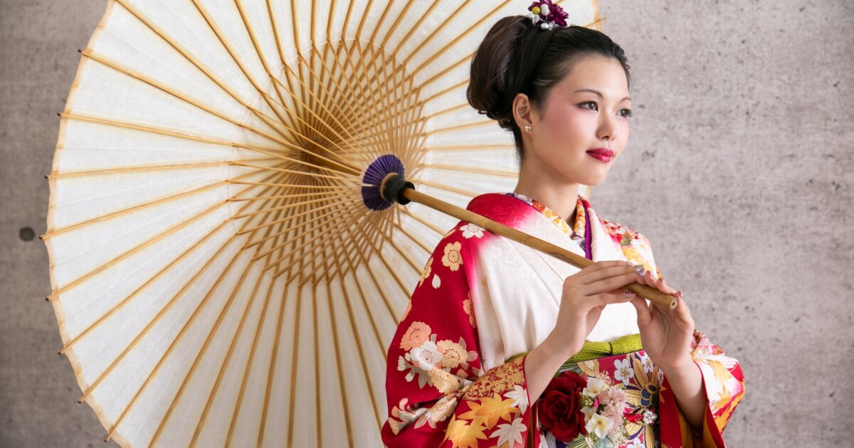 和傘を持った振袖姿の女性がポーズをとるスタジオ撮影