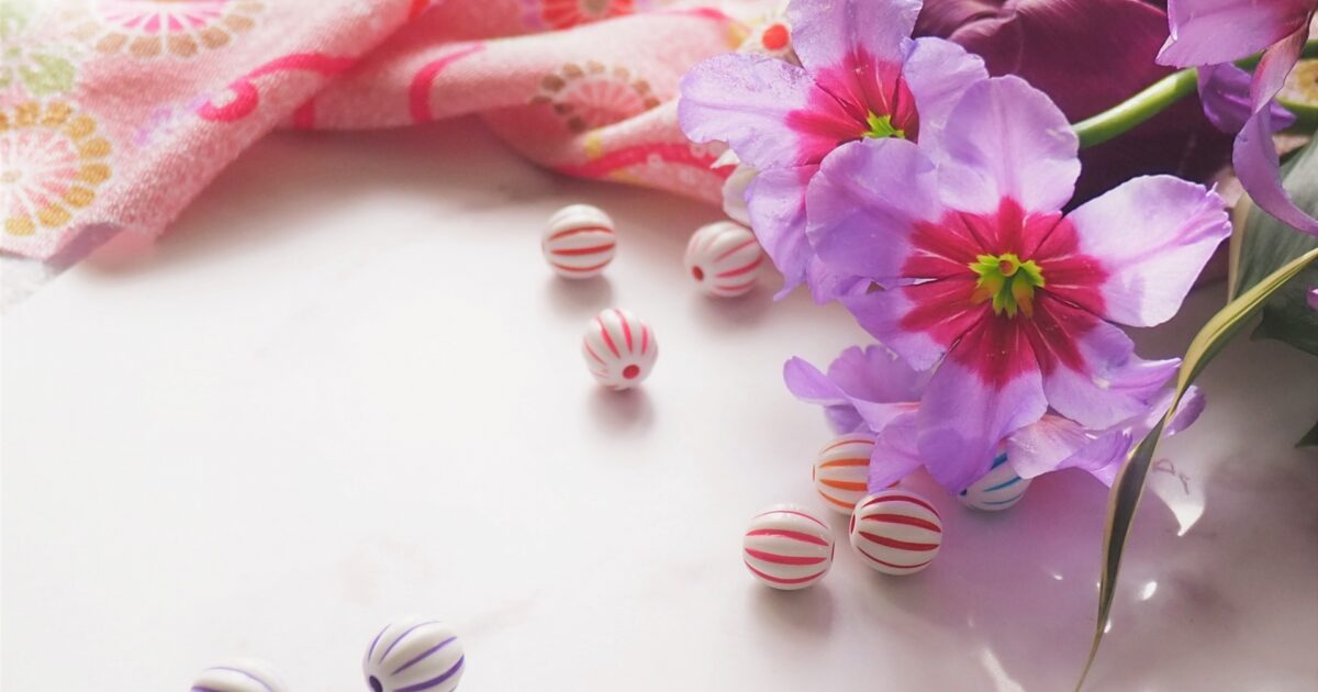 和柄の布と紫の造花とカラフルなストライプ模様のビーズ