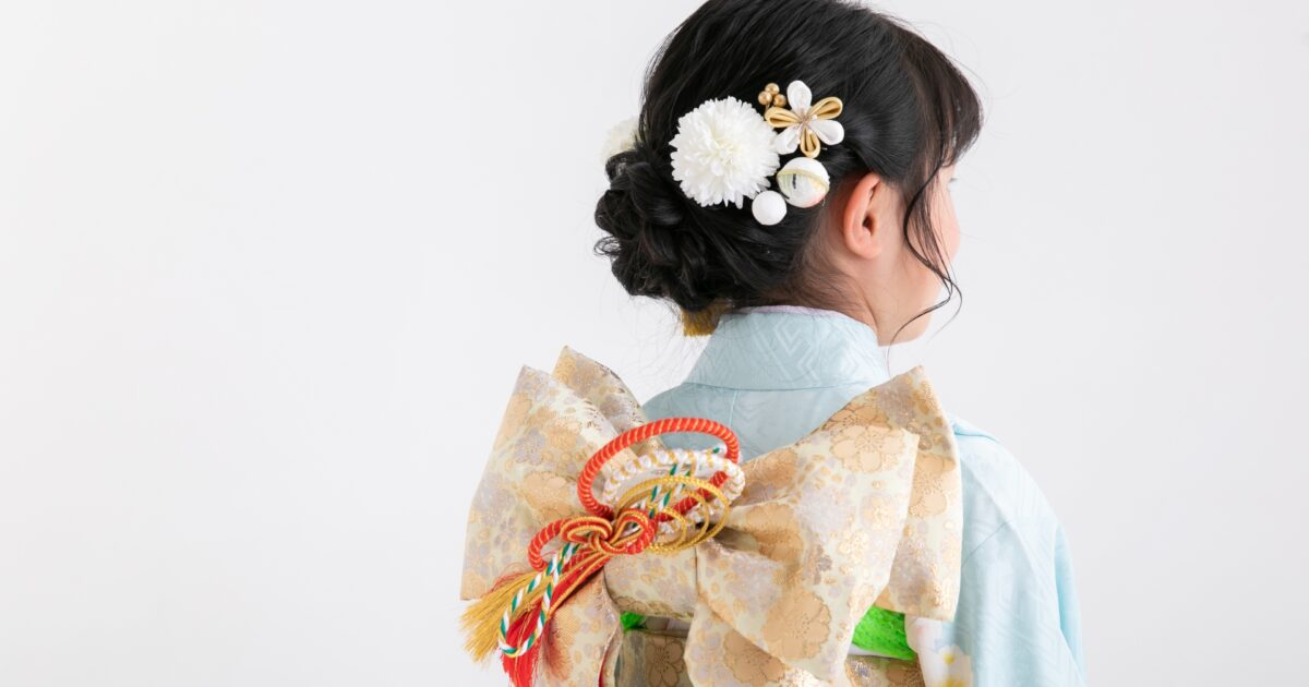 淡い水色の着物を着た女の子の後ろ姿と華やかな帯結び