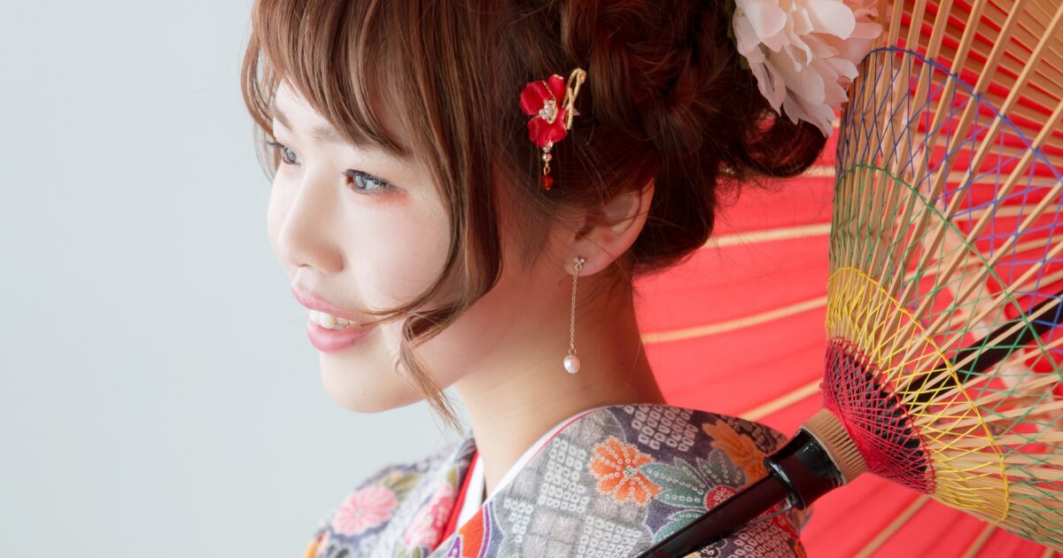 赤い和傘を差した振袖姿の女性の横顔と髪飾り