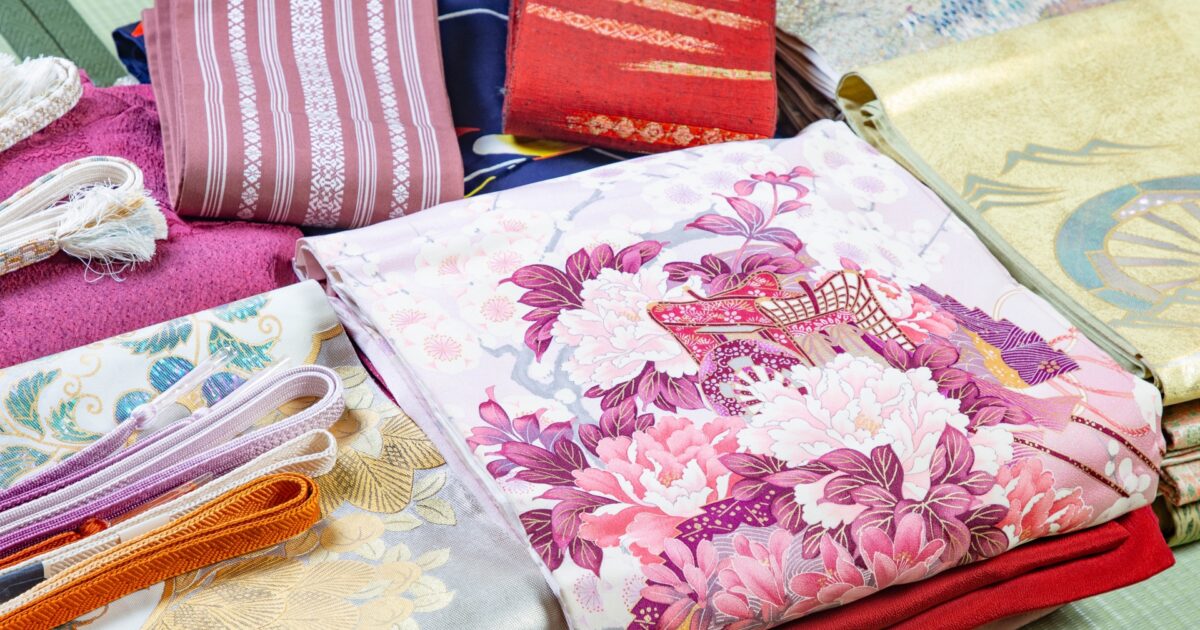 華やかな和柄の帯や帯締めが並ぶ畳の上のディスプレイ