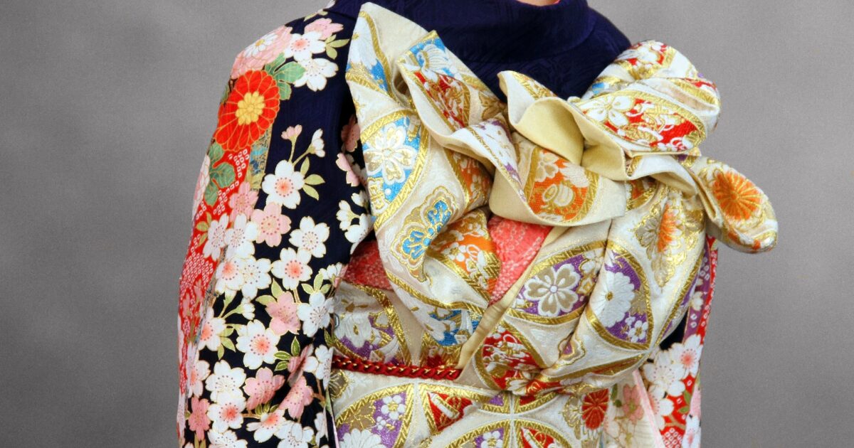 豪華な帯結びと花柄の振袖を着た女性の後ろ姿