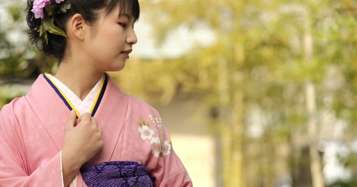 ピンクの着物を着た女性が髪飾りをつけて微笑む横顔