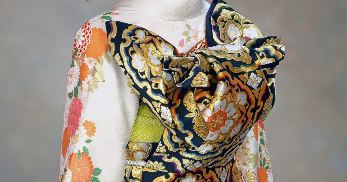 白地に花柄の振袖と黒金の豪華な帯結びの後ろ姿