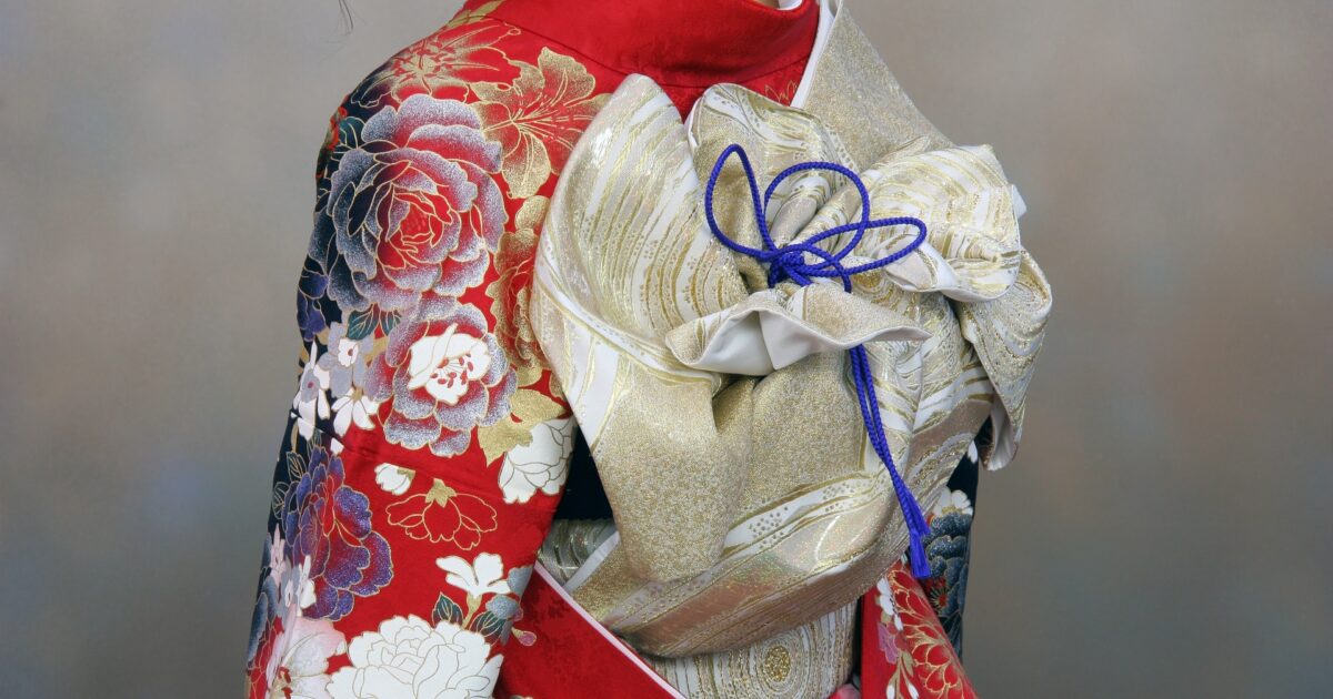 赤い振袖に金色の帯を結んだ女性の後ろ姿