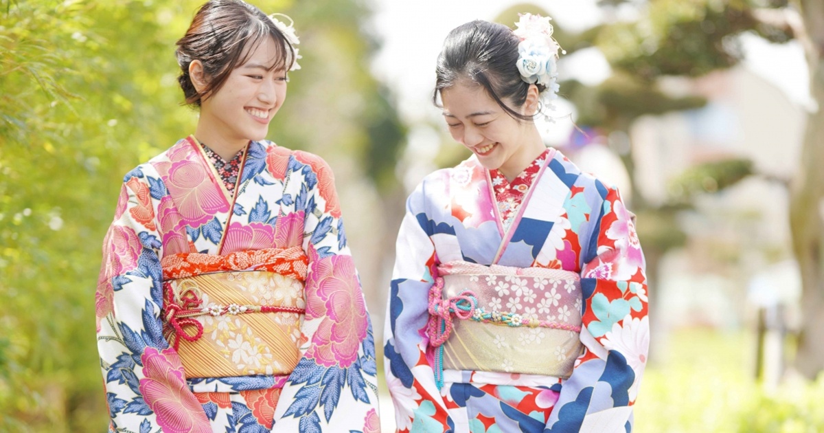 色鮮やかな着物を着た二人の女性が笑顔で並ぶ様子
