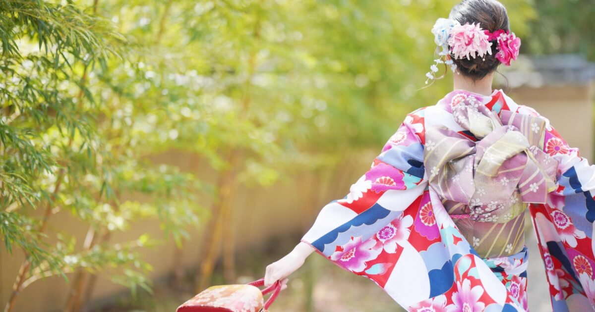 色鮮やかな着物姿の女性が腕を広げて歩く後ろ姿